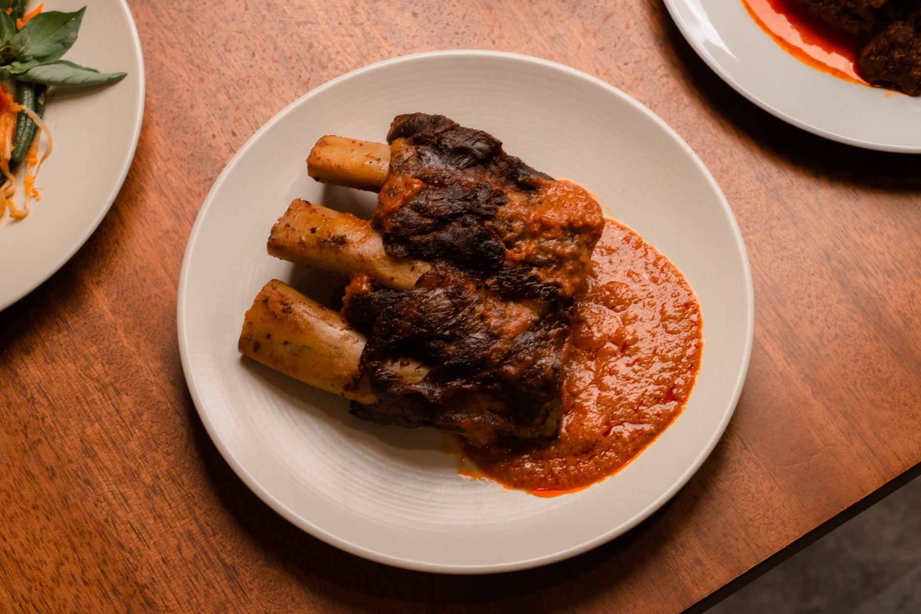 Falling-apart braised short ribs in a rich glaze on warm dark wood